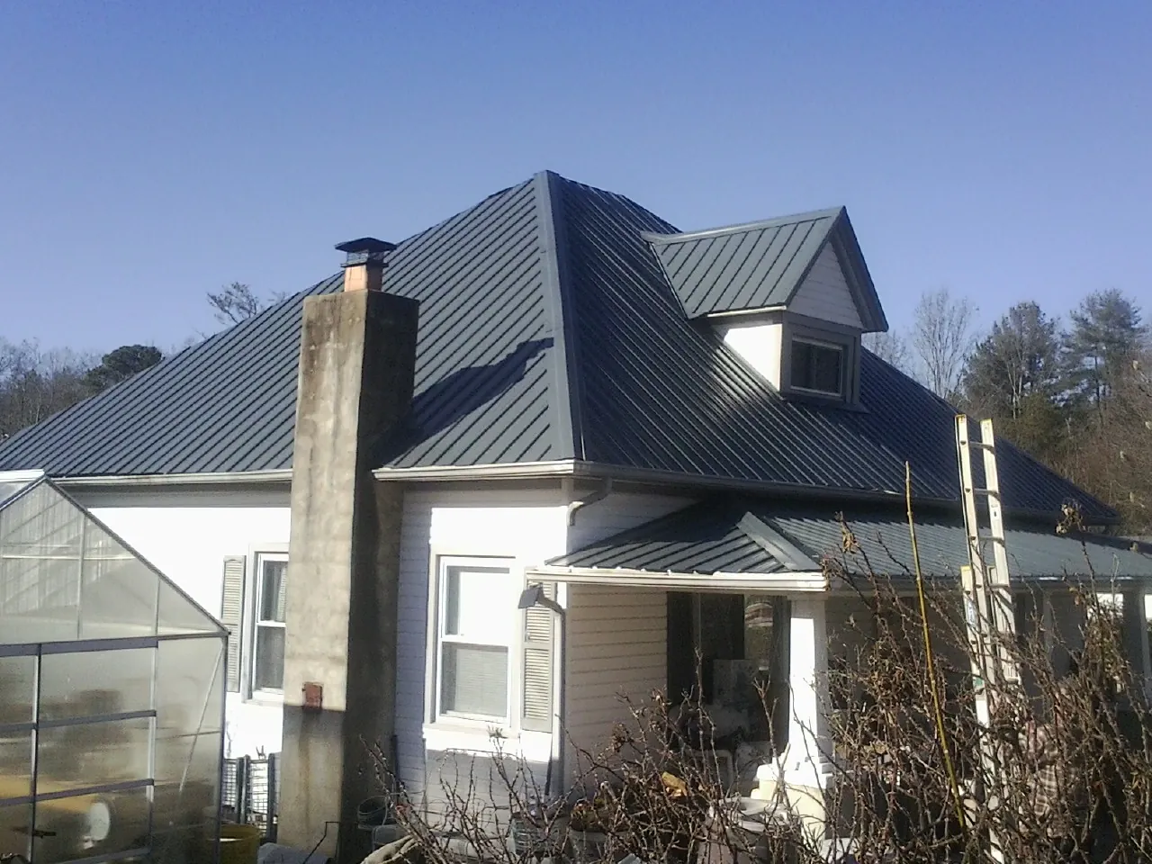 Dark blue standing seam metal roof on a white farmhouse with dormer — Slate & Tile Roof Repair by Roofing Brothers in Callicoon Center
