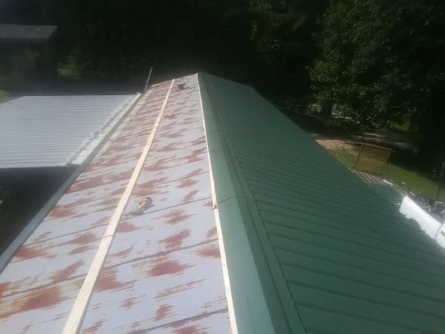 Old rusted panels beside newly installed green metal roofing — Wind Damage Roof Repair by Roofing Brothers in Callicoon Center