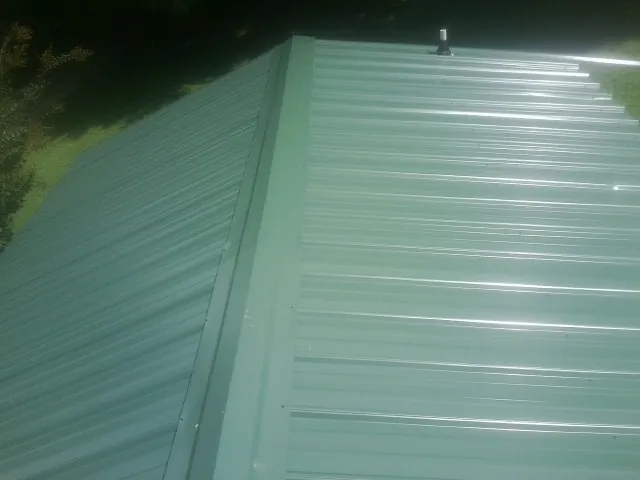 New green metal panels meeting at the ridge of a roof — Flat Roof Repair work by our crew in Callicoon Center