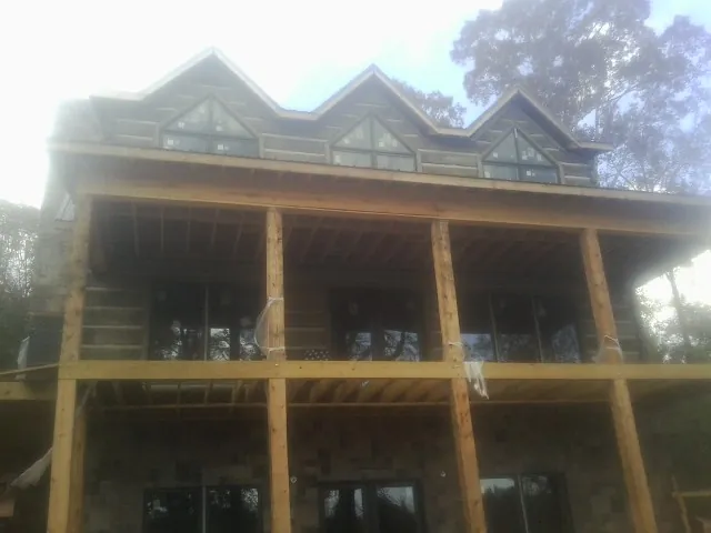 Dormers and porch framing on a large log home under construction — Roof Coating work by our crew in Callicoon Center
