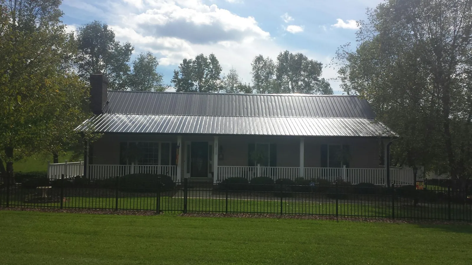 Gray metal roof on a brick ranch with a full width front porch — Gutter Guard Installation work by our crew in Callicoon Center