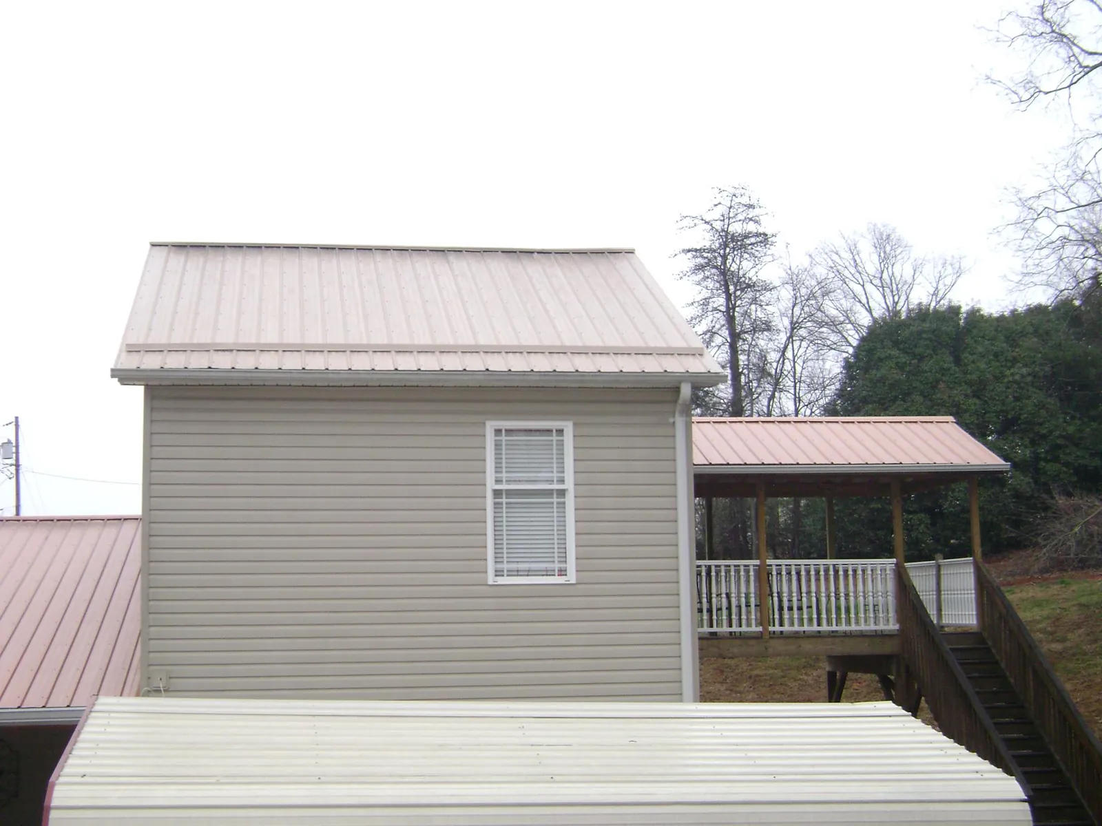 Tan metal roofs on a two story addition and attached porch, from a Roof Replacement job in Callicoon Center