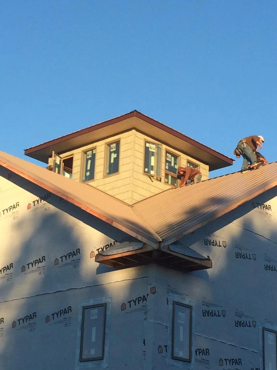 Roofers working around a rooftop cupola on a new metal roof at sunset — Roof Waterproofing in Callicoon Center by Roofing Brothers